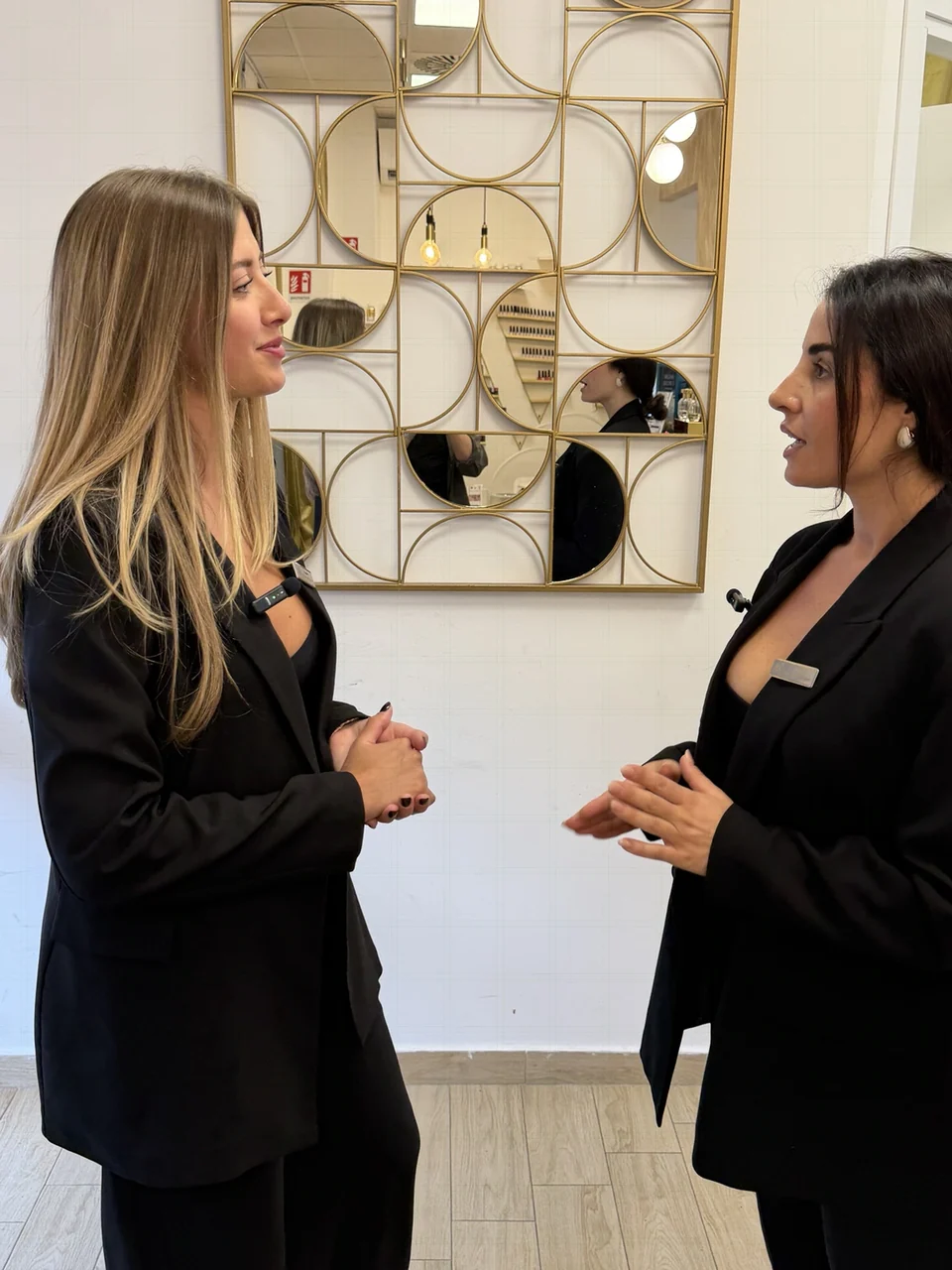 Giada e Luana in conversazione nel centro GL, davanti allo specchio geometrico dorato